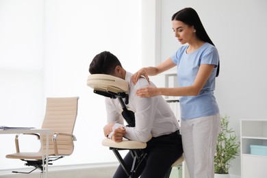 Man receiving massage in modern chair indoors