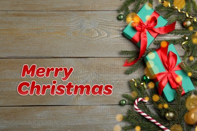 Image of Greeting card with phrase Merry Christmas. Beautiful fir tree branches, gift boxes and festive decor on wooden background, flat lay. Bokeh effect