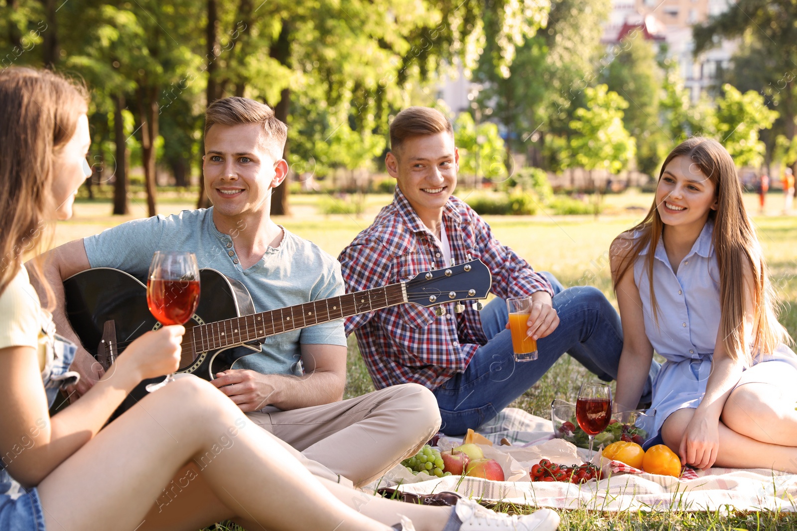 Photo of Young people enjoying picnic in park on summer day