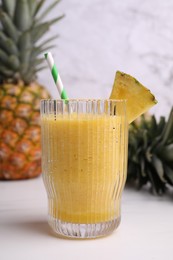 Photo of Tasty pineapple smoothie and fresh fruits on white table