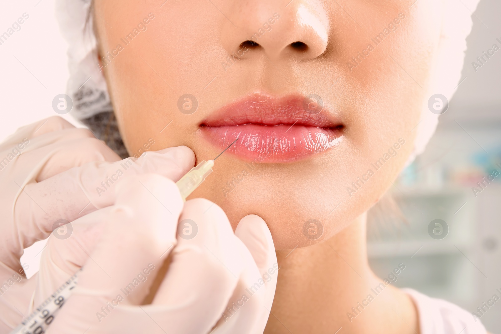 Photo of Young woman getting lip injection in beautician salon, closeup