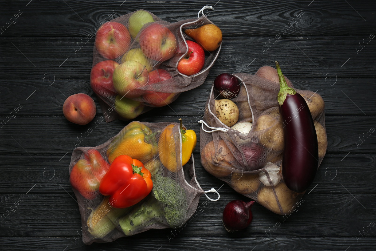 Photo of Different fresh vegetables in bags on black wooden table, flat lay. Farmer harvesting