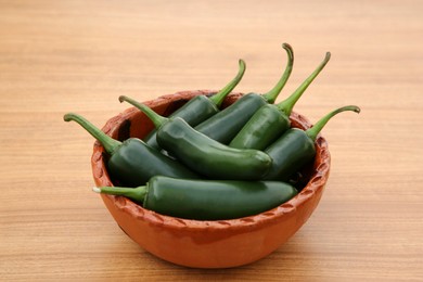 Bowl of fresh green jalapeno peppers on wooden table