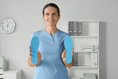 Beautiful female orthopedist showing insole in hospital