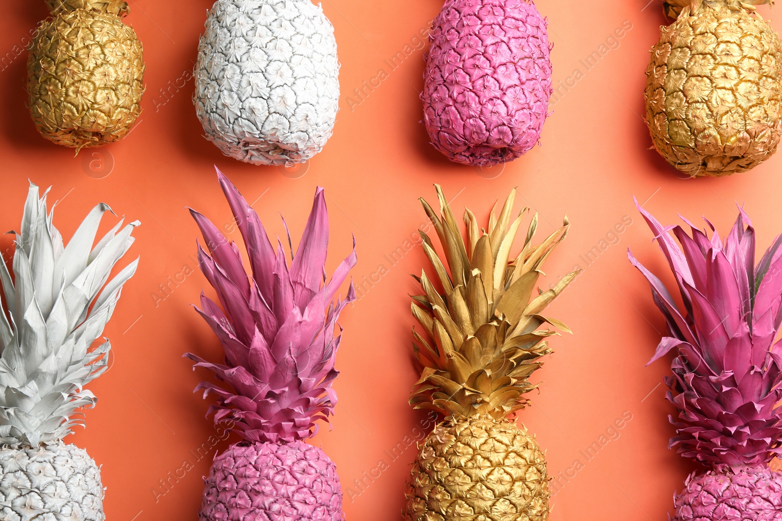 Photo of Many colorful pineapples on orange background, flat lay. Creative concept