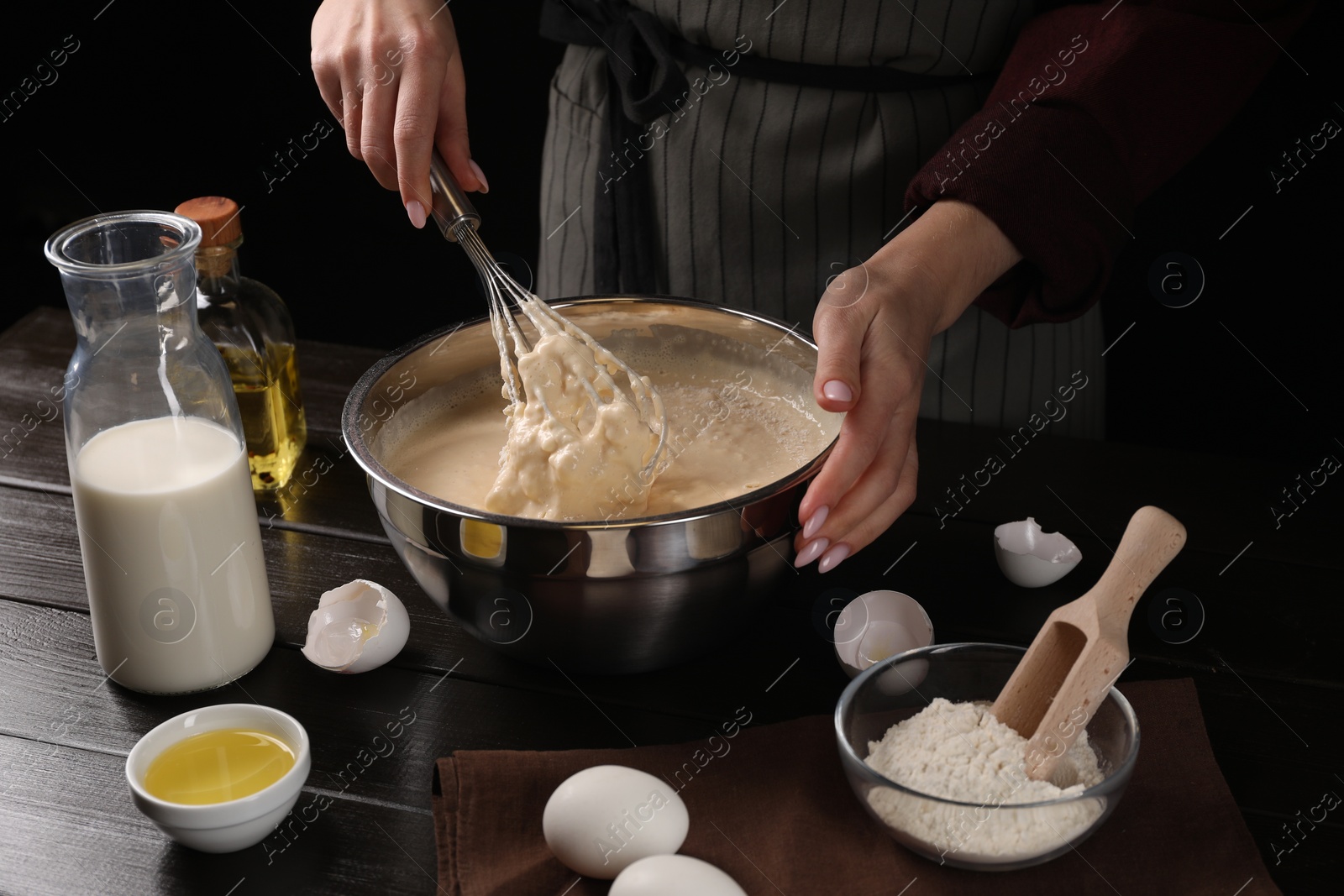 Photo of Woman making dough with whisk in bowl at table, closeup