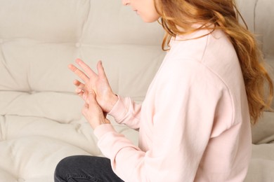 Photo of Woman suffering from trigger finger on sofa, closeup