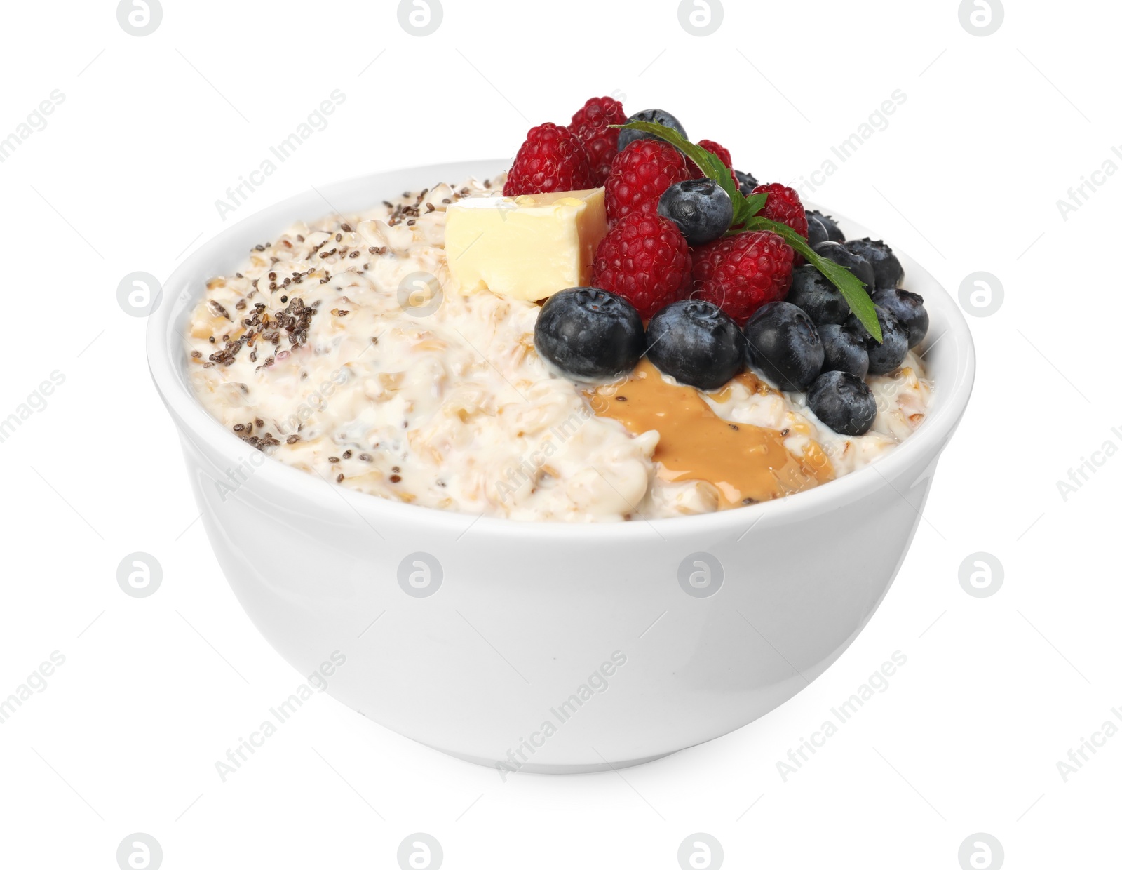 Photo of Tasty boiled oatmeal with berries, chia seeds and peanut butter in bowl isolated on white