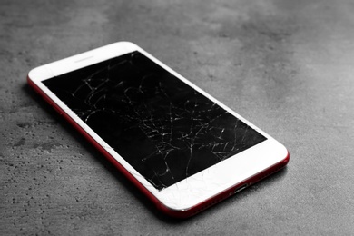 Modern smartphone with broken display on table. Device repair service