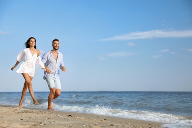 Happy young couple running together on beach