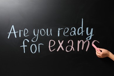 Photo of Woman writing phrase Are You Ready For Exams on blackboard, closeup