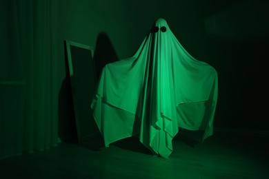 Creepy ghost. Woman covered with sheet in green light