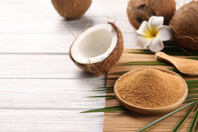 Photo of Coconut sugar, palm leaves, fruits and bamboo mat on wooden rustic table, closeup. Space for text