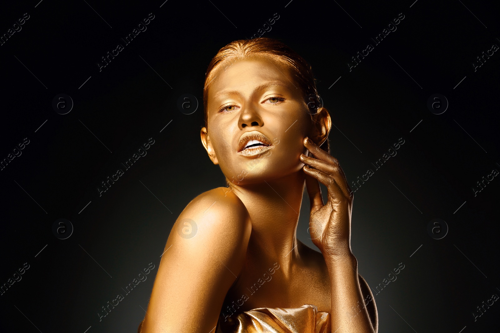 Photo of Portrait of beautiful lady with gold paint on skin against black background