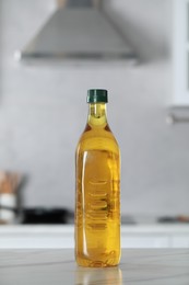 Photo of Bottle of cooking oil on white marble table in kitchen