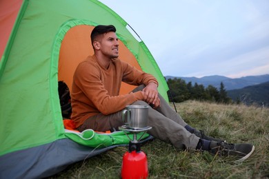 Man enjoying mountain landscape in camping tent