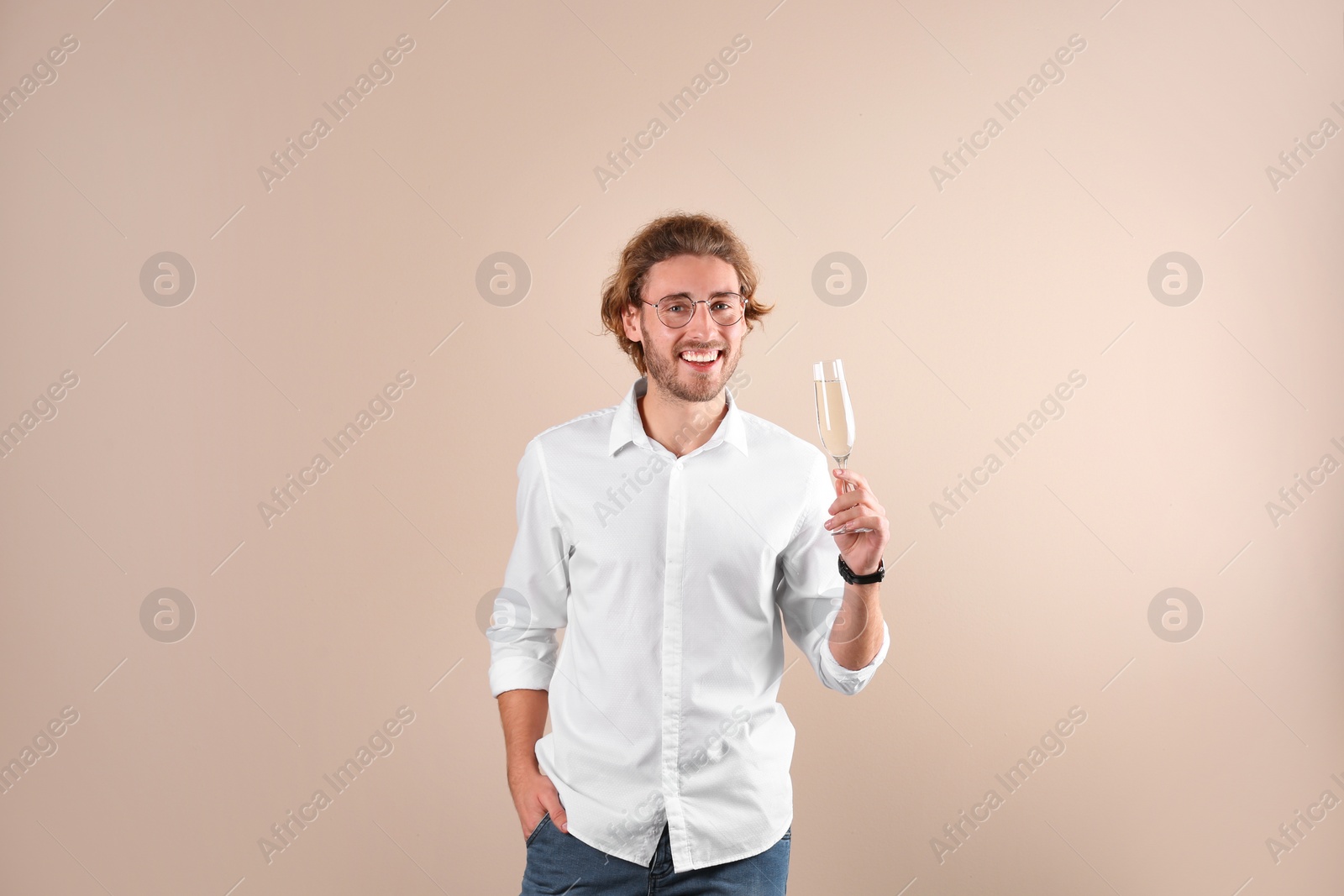 Photo of Portrait of happy man with champagne in glass on color background