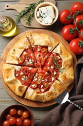 Flat lay composition of tasty galette with tomato, rosemary and cheese (Caprese galette) on wooden table