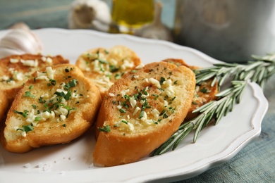 Photo of Plate with delicious homemade garlic bread on table, closeup