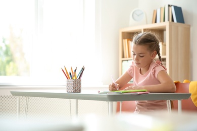 Photo of Cute little child doing assignment at desk in classroom. Elementary school