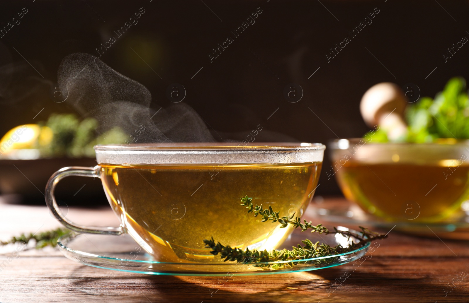 Photo of Cup of aromatic herbal tea and fresh thyme on wooden table