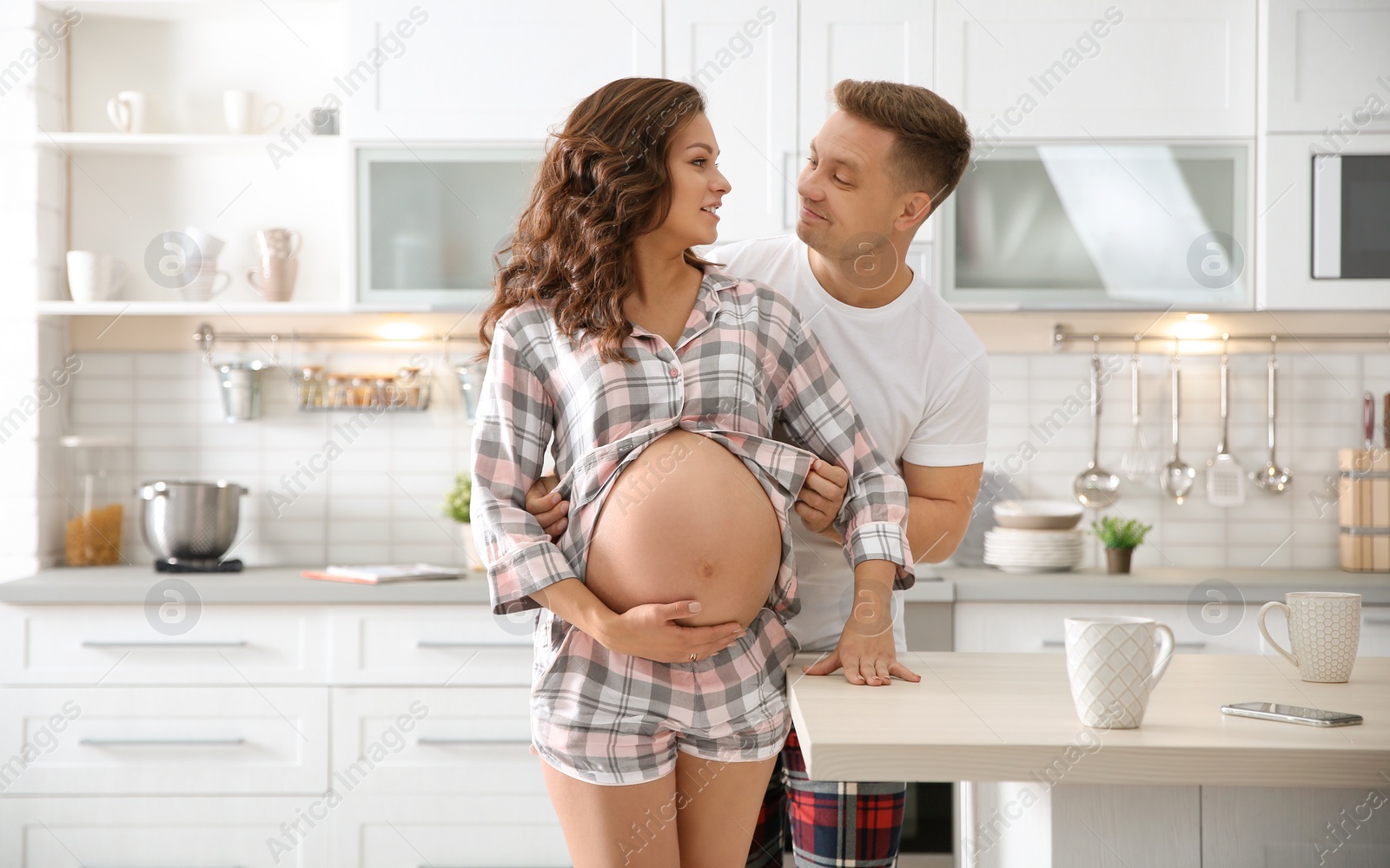 Photo of Pregnant woman with her husband in kitchen. Happy young family