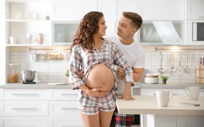 Pregnant woman with her husband in kitchen. Happy young family