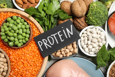 Photo of Card with word PROTEIN and different products on table, flat lay