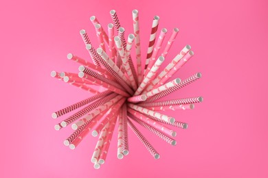 Many paper drinking straws on pink background, top view