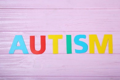 Photo of Word AUTISM on color background, top view