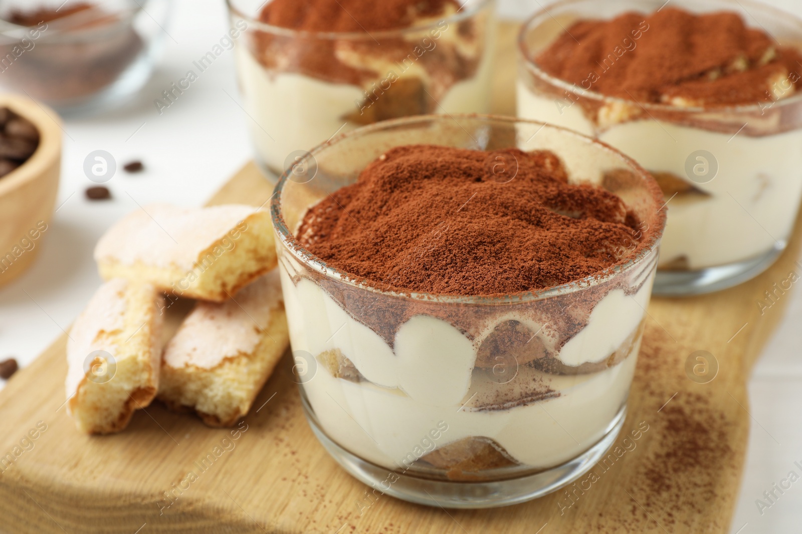 Photo of Delicious tiramisu in glasses and cookies on table, closeup