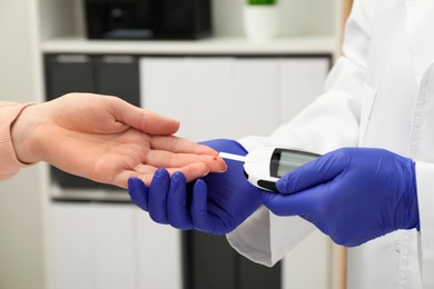 Diabetes. Doctor checking patient's blood sugar level with glucometer in clinic, closeup