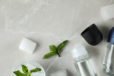 Flat lay composition with roll-on deodorants on light grey marble table