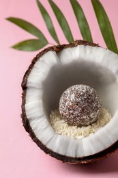 Composition with delicious vegan candy ball and coconut on pink background