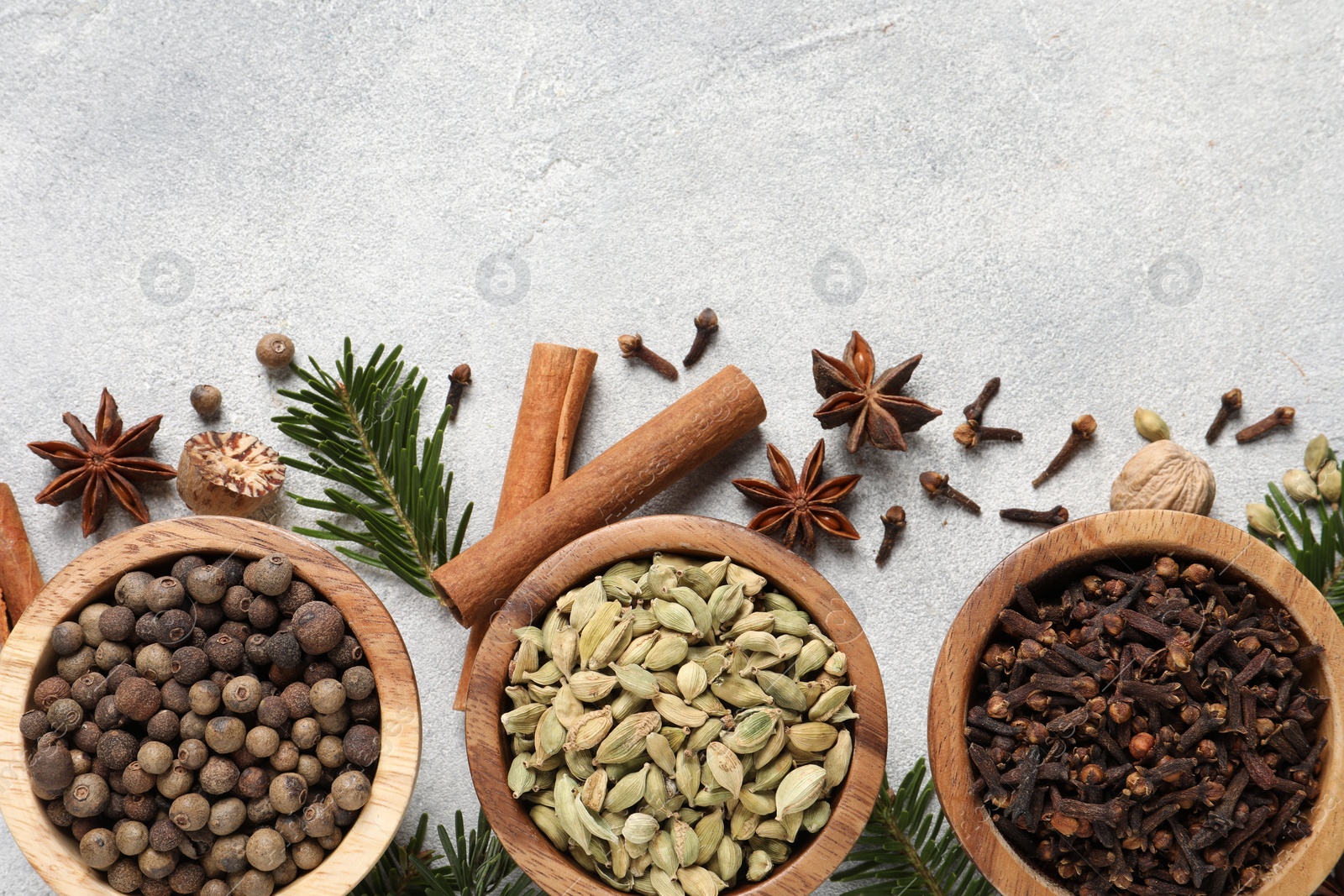 Photo of Different aromatic spices and fir branches on light textured table, flat lay. Space for text