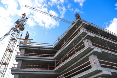 Photo of Unfinished building against blue sky. Construction safety rules