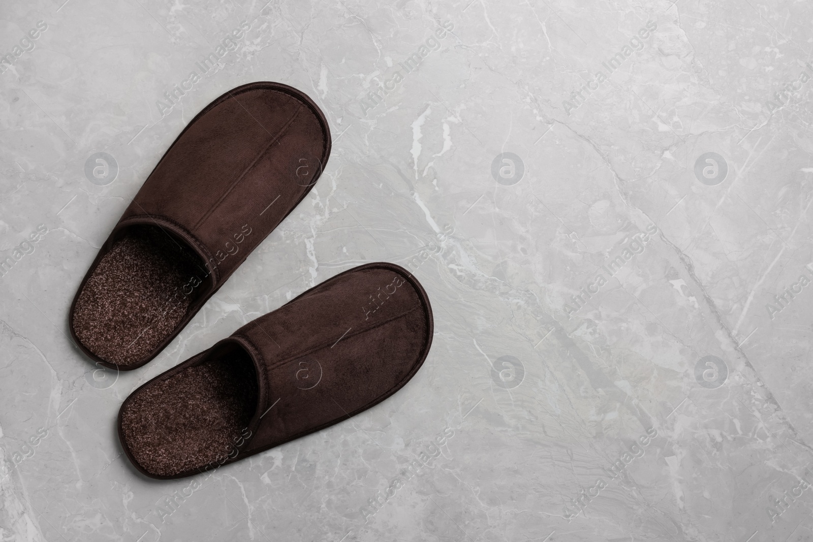 Photo of Pair of brown slippers on grey marble floor, top view. Space for text