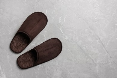 Pair of brown slippers on grey marble floor, top view. Space for text