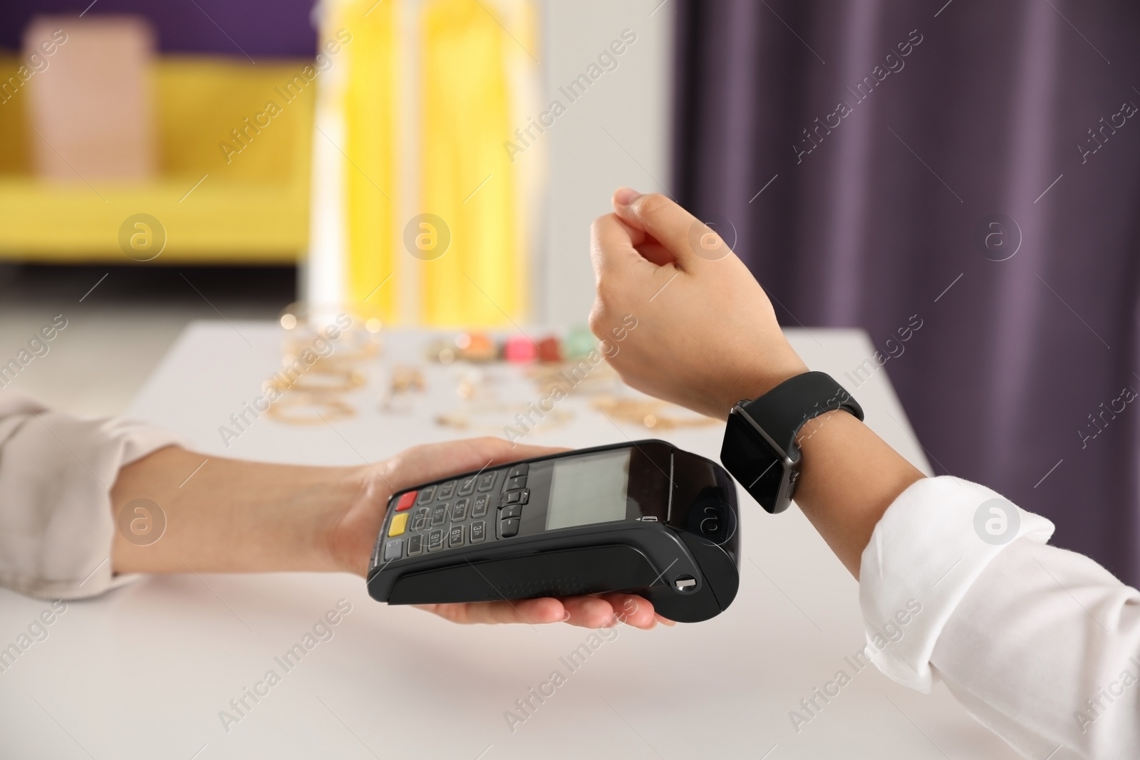 Photo of Woman using terminal for contactless payment with smart watch in shop, closeup