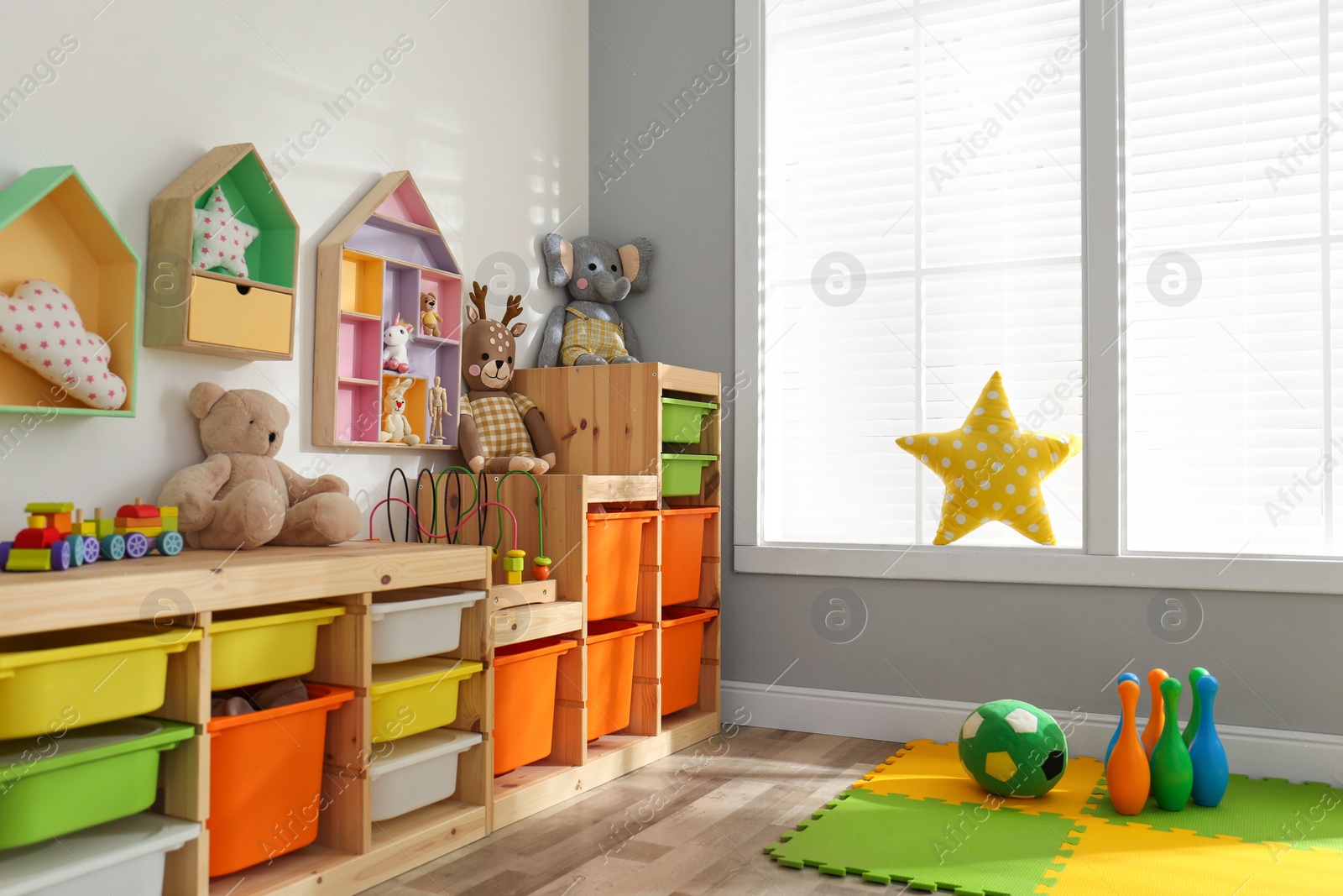 Photo of Stylish playroom interior with shelving unit and different soft toys