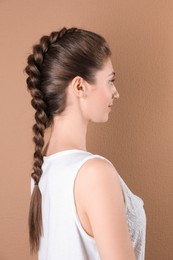 Photo of Woman with braided hair on light brown background