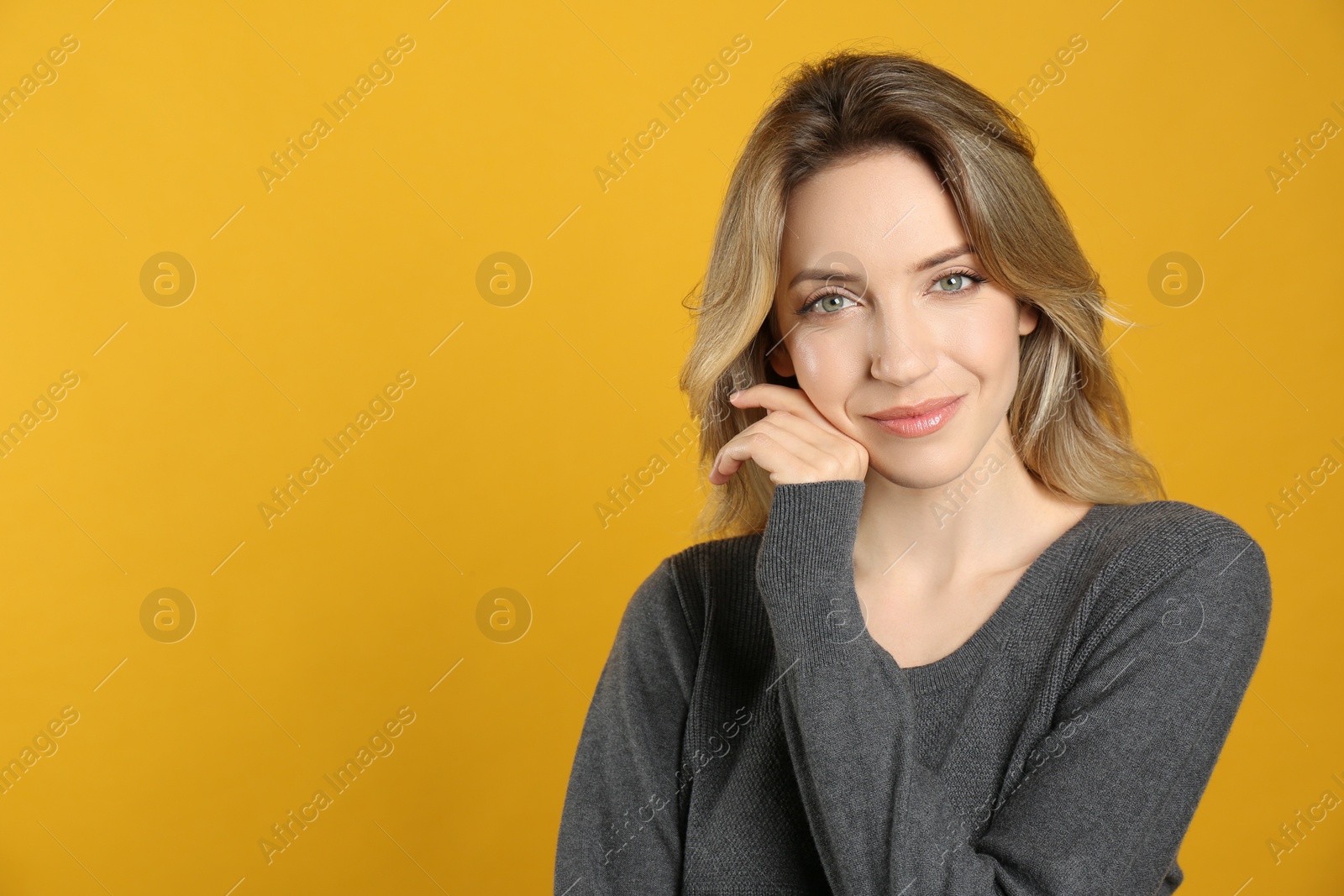 Photo of Portrait of happy young woman with beautiful blonde hair on yellow background. Space for text