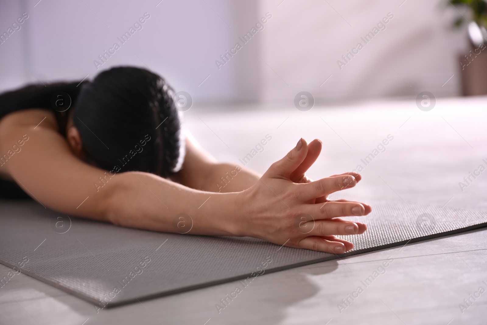Photo of Young woman practicing extended child's asana in yoga studio, closeup. Utthita Balasana pose