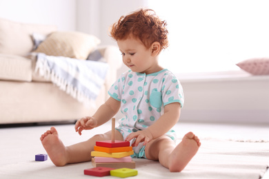 Photo of Cute little child playing with toy on floor at home