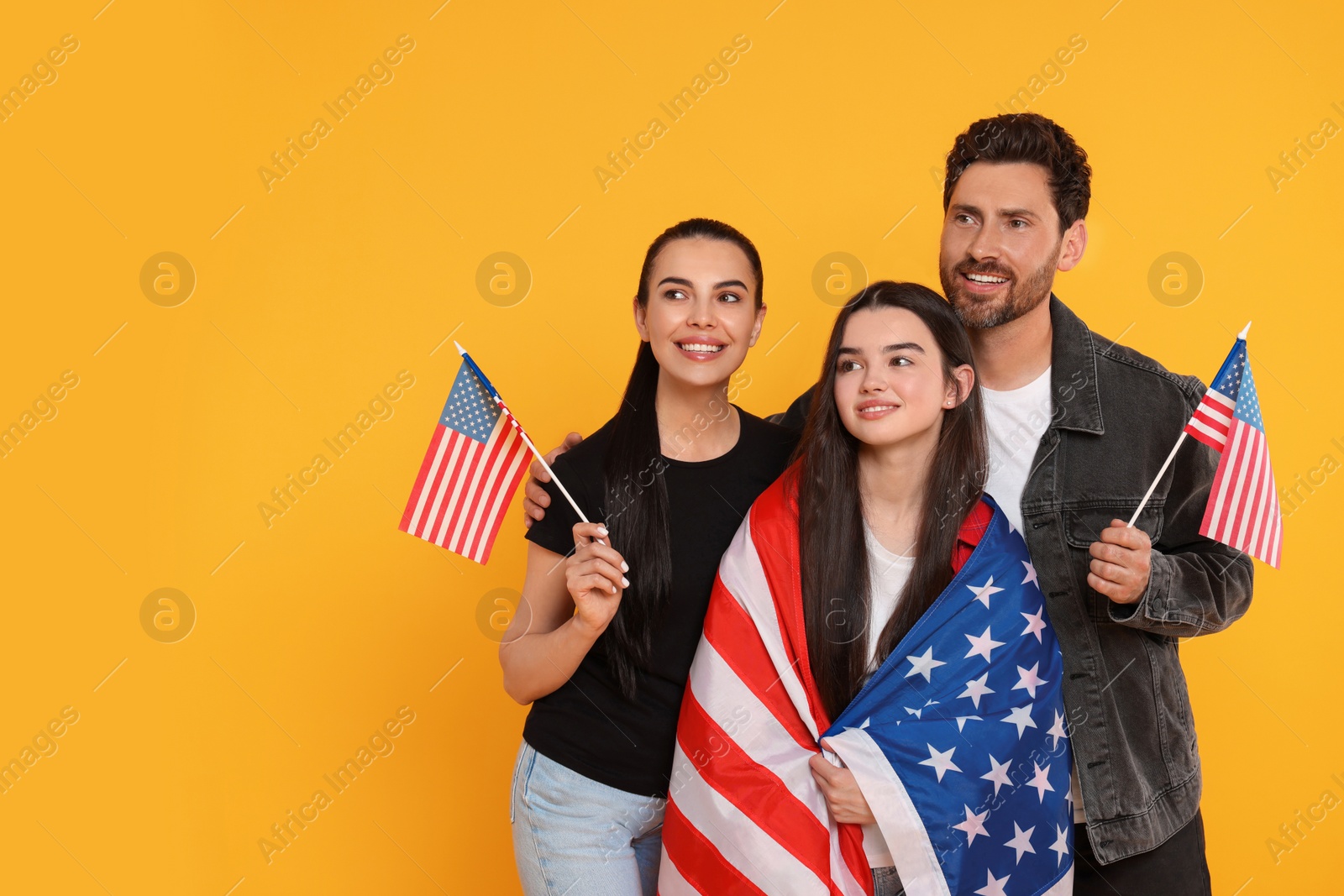 Photo of 4th of July - Independence Day of USA. Happy family with American flags on yellow background, space for text