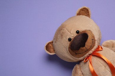 Photo of Cute teddy bear on light purple background, top view. Space for text