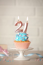 Photo of 21th birthday. Delicious cupcake with number shaped candles for coming of age party on table
