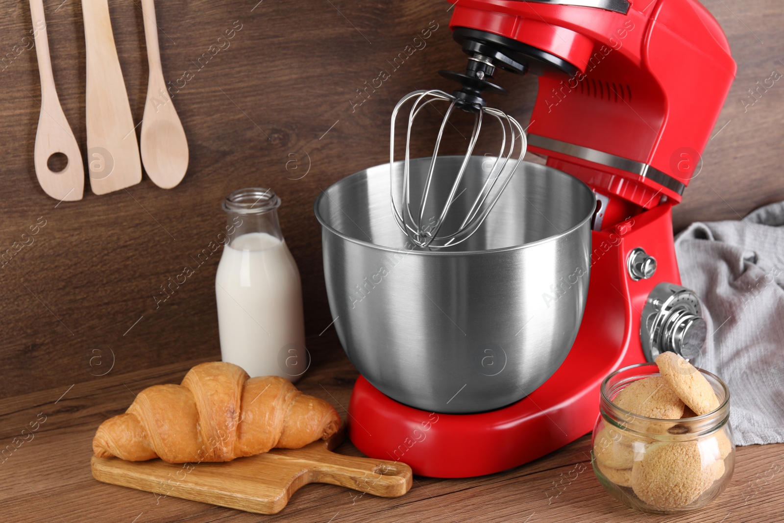 Photo of Modern red stand mixer, croissant and cookies on wooden table