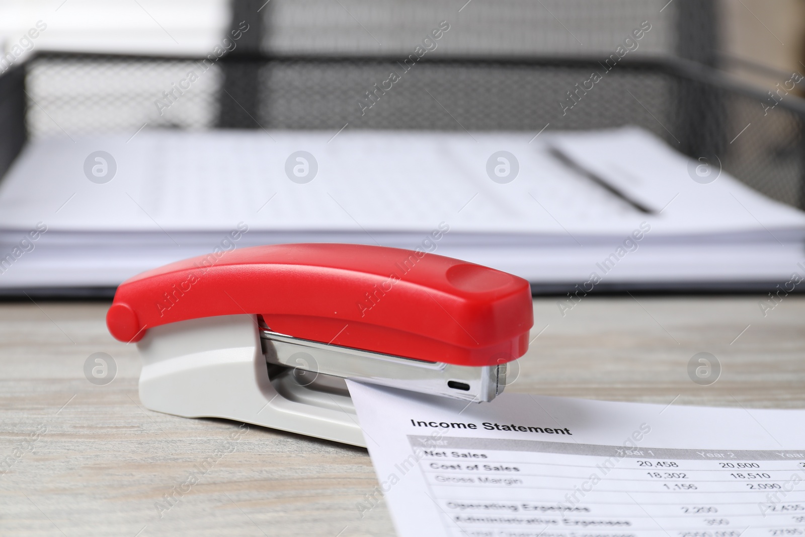 Photo of Stapler with document on wooden table, closeup