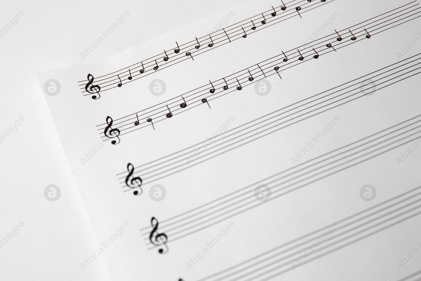 Photo of Sheet of paper with music notes on white background, closeup view